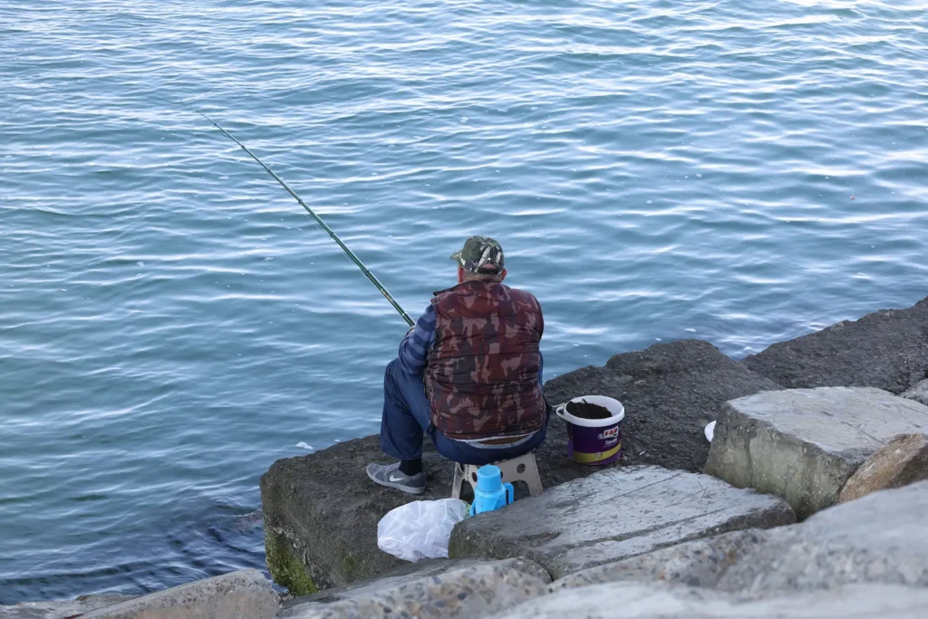 Hombre sentado pescando en rio